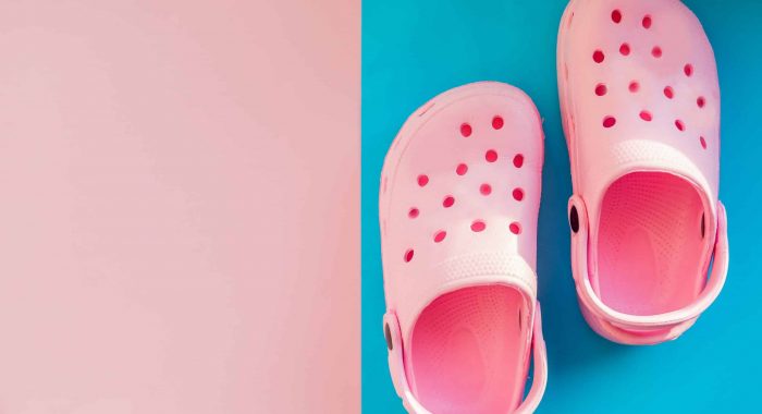 Pink baby sandals on a reflective surface. Beach fashion