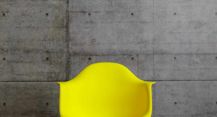 Yellow plastic modern design armchair on wooden stands