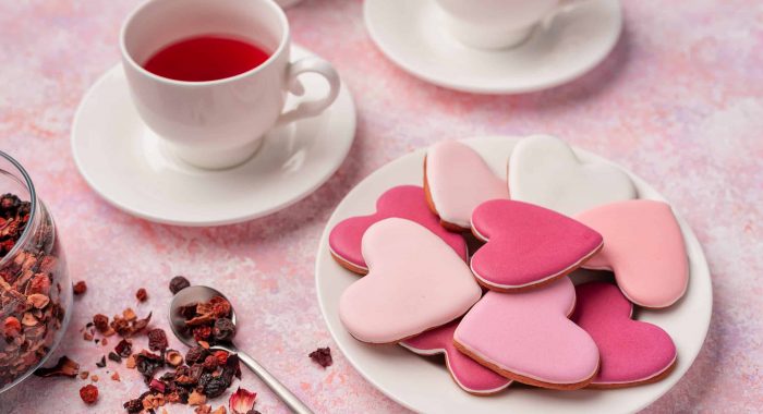 Heart shape cookies with icing with berry tea. Concept: Valentine's Day tea party, festive table setting in pink.