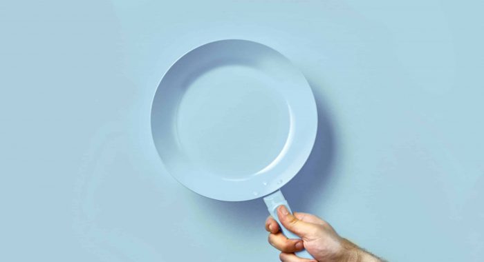 Colored pan in the hand. A hand is holding a  pan on a colored background. Colored pan isolated. Cooking food concepts