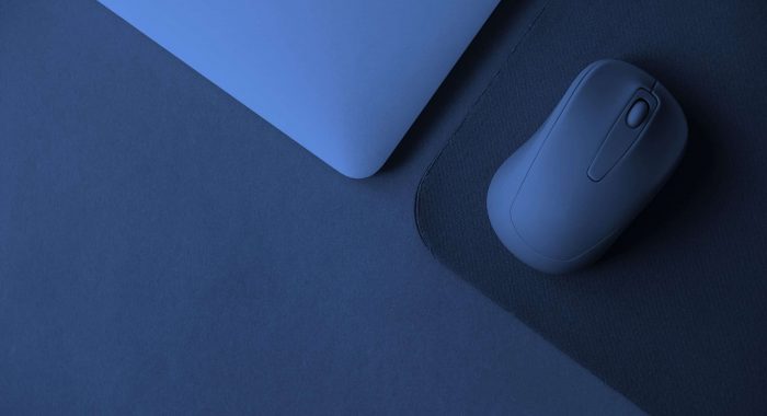 Computer mouse with notebook and mouse pad on blue background, dark blue tones image for background