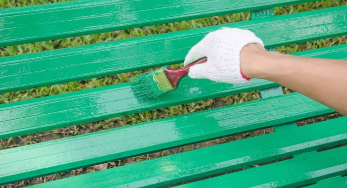 Hand holding brush painting timber wall