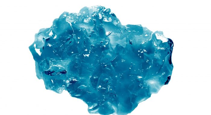 Jelly piece isolated on white background. Blue cosmetic gel texture. Jelly soap, mask, cream swatch. Abstract colored gelatin product sample