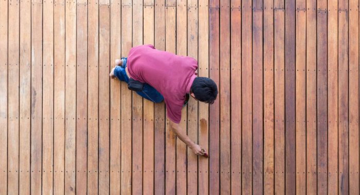 A worker painting exterior wooden pool deck, Top view