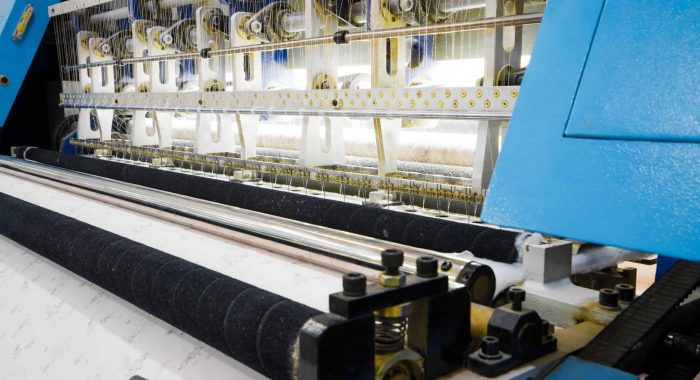 weaving loom at a textile factory, closeup. industrial fabric production line
