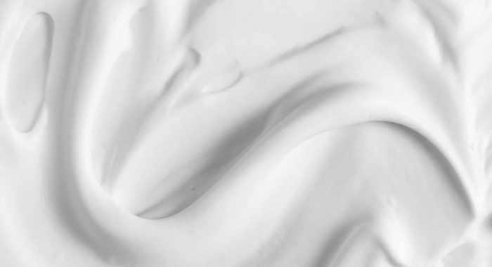 White cosmetic foam texture background. Cosmetic mousse, cleanser, shaving foam, shampoo. Foamy skin care product