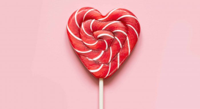 Valentine's card. Lollipops candy as heart on pink background. Funny concept.