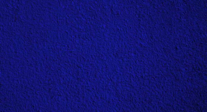 Rough navy blue painted plaster or stucco wall. Toned. Abstract grunge background with copy space. Close-up.