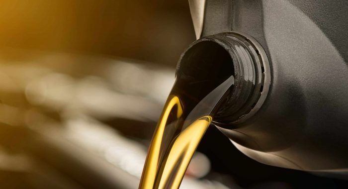 Pouring oil lubricant motor car from black bottle on isolated white background