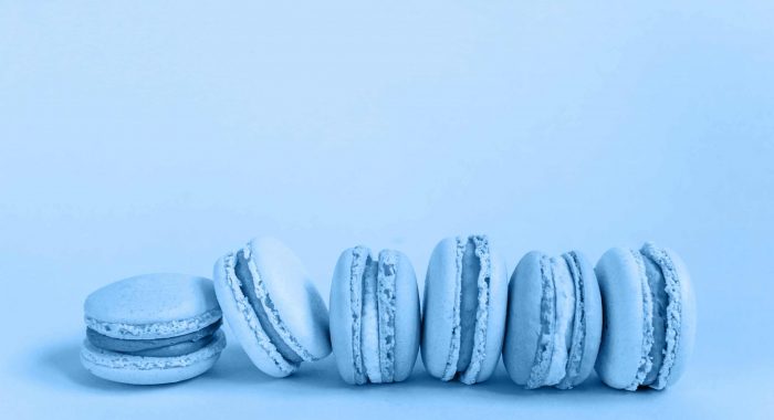 Sweet almond macaron or macaroon dessert cake colored in trendy color of year 2020 Classic Blue isolated on blue pastel background. Macro using color 19-4052. Copy space.