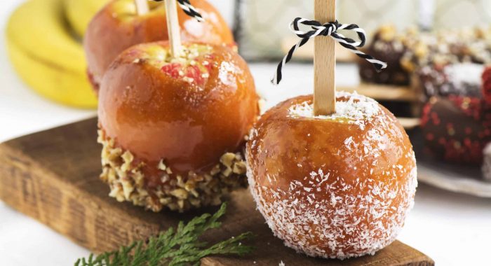 Traditional halloween party dessert: caramelized apples decorated with sprinkles, nuts and coconut chips. Selective focus