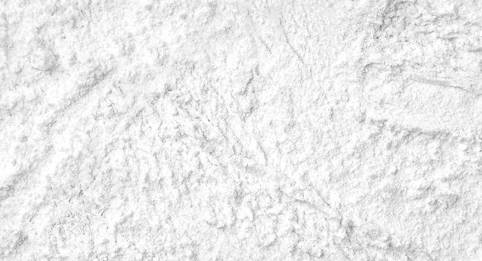 Flour close up background. A pile of flour on a white background. Spilled flour. Flour texture