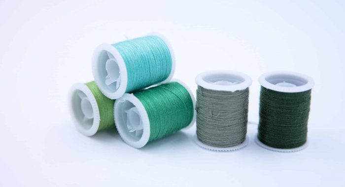Roll of thread put on white background,group of green color,for needle work,blurry light around