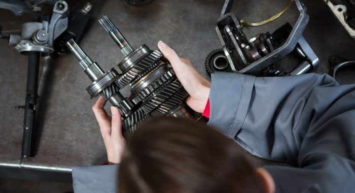 Female mechanic holding spare parts at repair garage