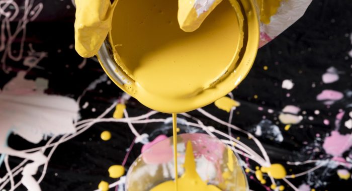 hand-pouring-yellow-paint-from-can